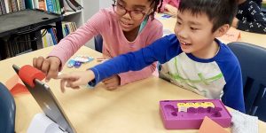 Image of two children learning Scratch coding and pointing at an iPad together.