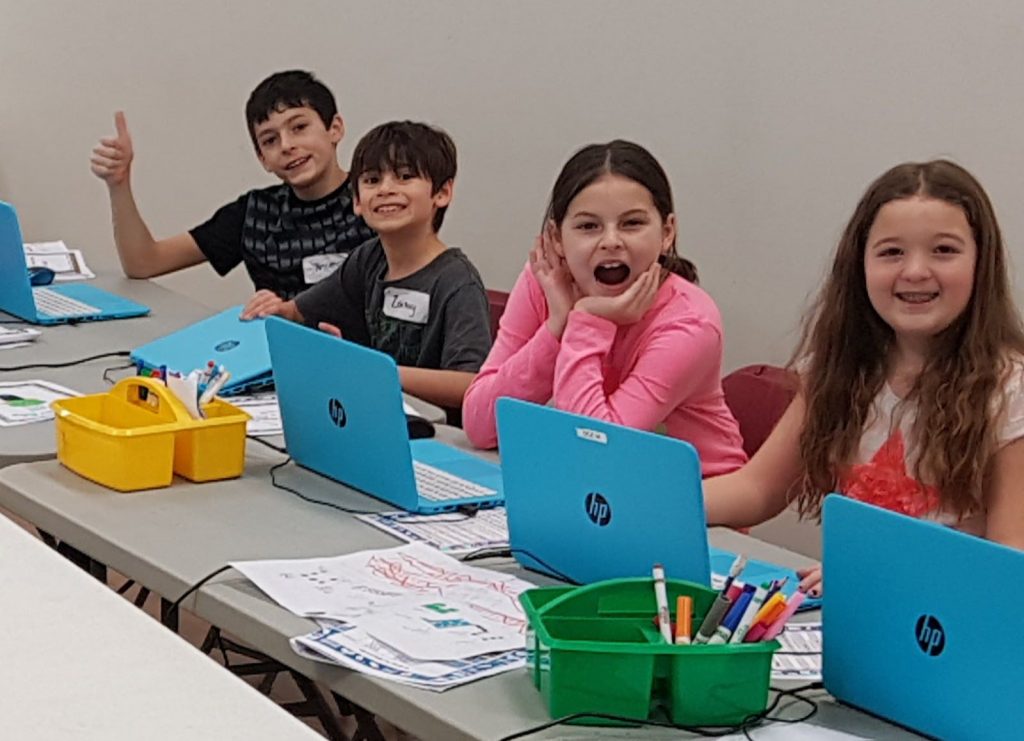 Boys and Girls smile as they work on computer science and coding projects in a minecraft summer camp in edmonton